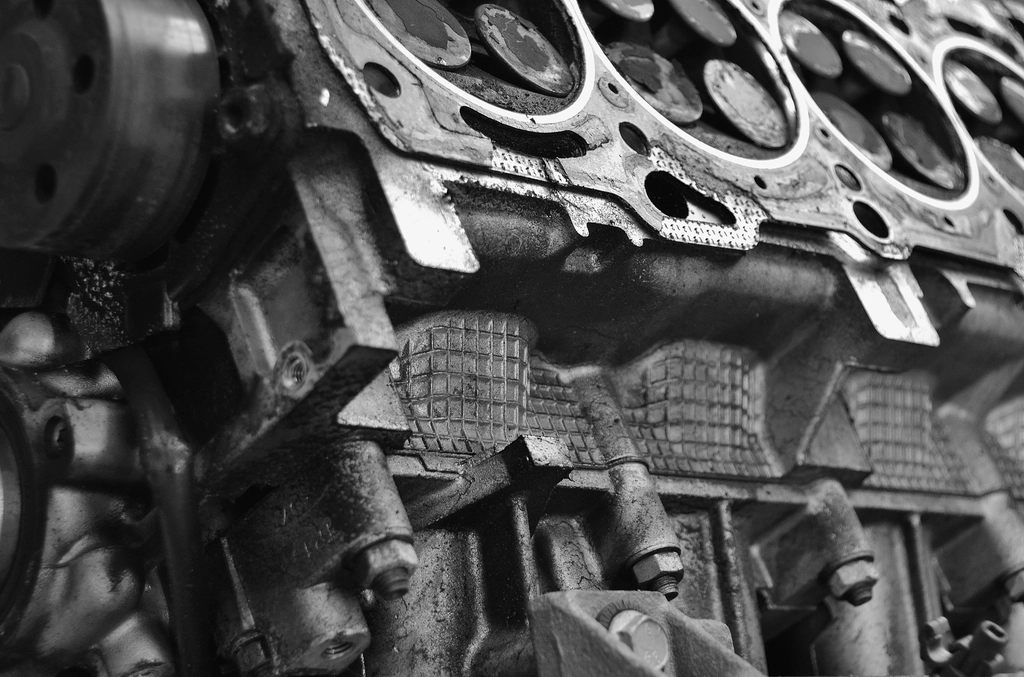 Zwart-witfoto van een geopend motorblok met cilinderkop en pakking